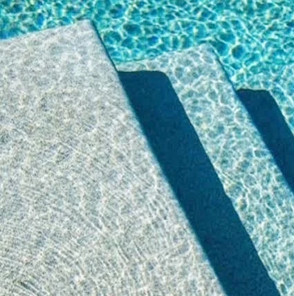 Close-up of a pebblecrete pool interior finish, showing the pebble and cement texture underwater